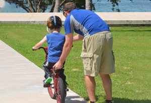 A man teaching his son how to ride a bike.