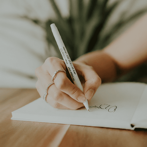 A person writing on paper with a pen.